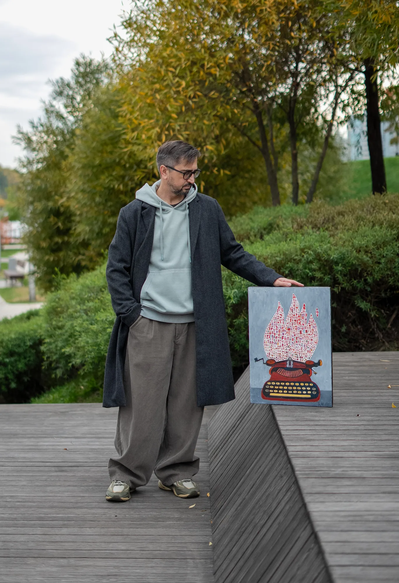 Sergei Nikolaev standing outdoors beside one of his paintings